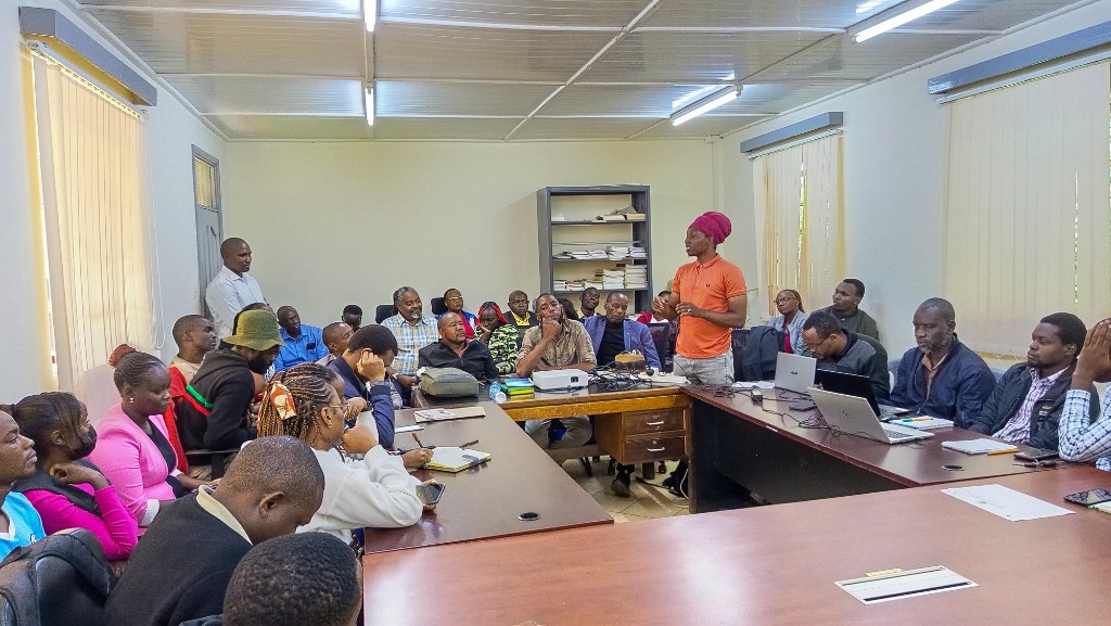 Plenary discussion with participants seated around tables in Mathare Umoja, Kajiado County